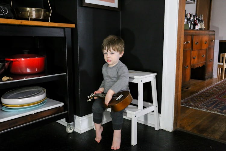 Emily Farris's son sitting on a tiny chair near the open kitchen shelving in the Boozy Bungalow