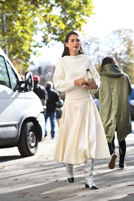 A woman walking the street in white midi skirt and a matching sweater