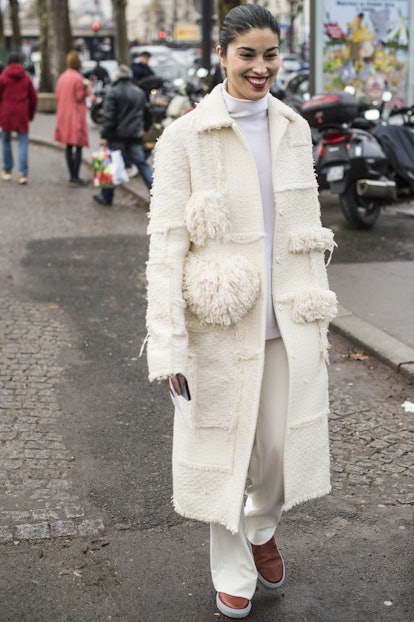A woman wearing white pants and turtleneck under a white coat with mixed textures 