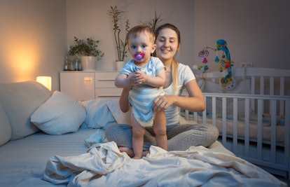 A mother holding her toddler while sitting on the bed
