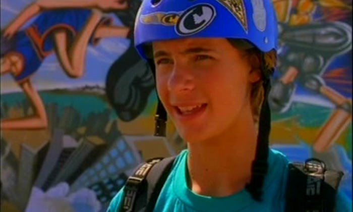 Erik Von Detten wearing a helmet and a backpack in front of a wall of graffiti