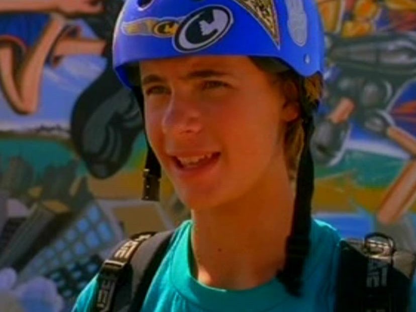 Erik Von Detten wearing a helmet and a backpack in front of a wall of graffiti