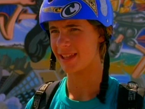 Erik Von Detten wearing a helmet and a backpack in front of a wall of graffiti