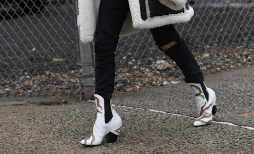 A woman walking in black skinny jeans and white ankle boots