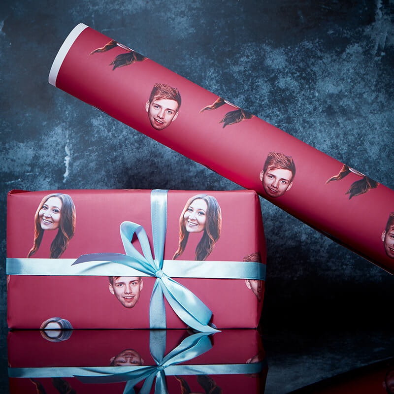 A roll of wrapping paper with a person's face on it and a gift wrapped in it