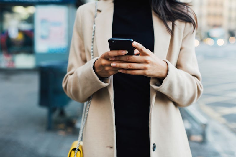 A woman typing on her phone while walking down a street