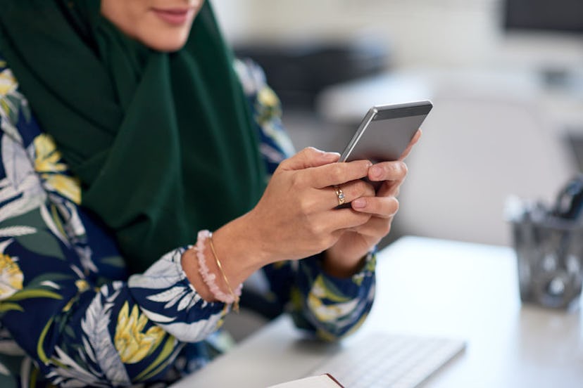 A woman typing on her phone while sitting at a desk