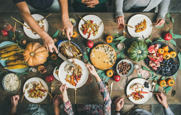 A photo of a large Thanksgiving spread taken from above, while everyone around the table serves them...