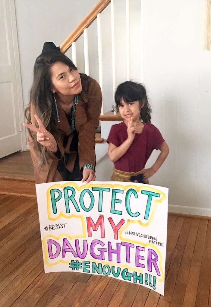 An Indigenous mom and her daughter posing with a sign that says "protect my daughter"