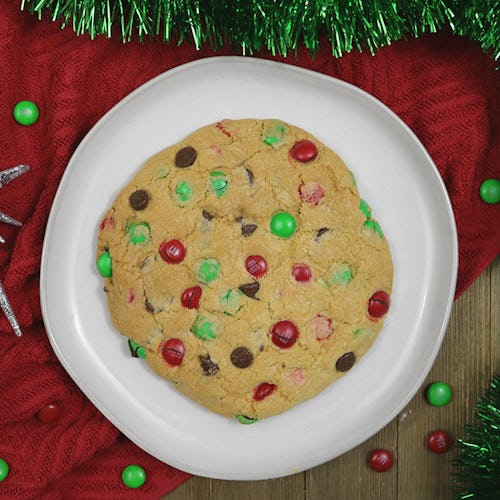 A Christmas cookie served on a plate with a red blanket beneath and green tinsel garland around it