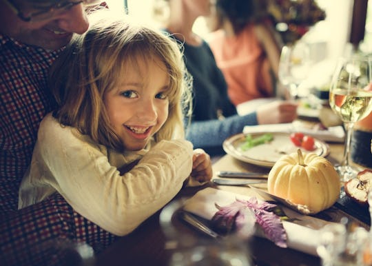 a little girl sitting at the thanksgiving dinner table