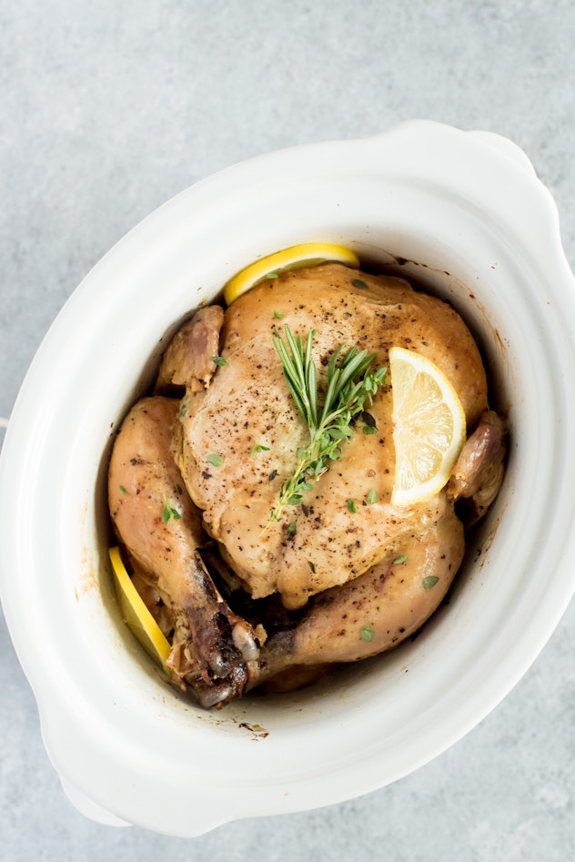 whole chicken garnished with a sprig of rosemary and  lemon in a white pot