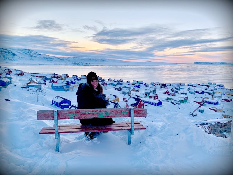 Collette Reitz sitting on a bench posing for a picture in Ittoqqortoormiit, Greenland