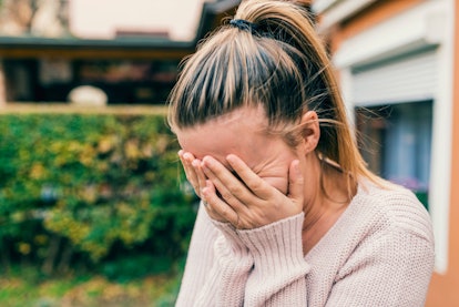 Woman crying, covering her face with her hands due to her leaky gut syndrome