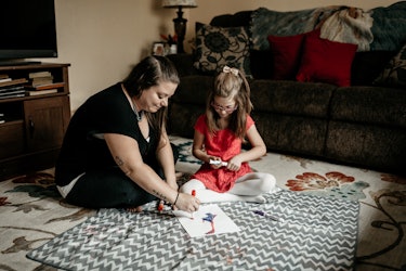 Megan and her daughter painting and sitting on the floor