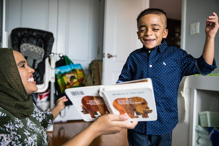 Mother sitting on the floor and showing her happy and smiling son the picture book.