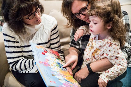 A mother holding her daughter who has Epilepsy as they read a book about flowers together