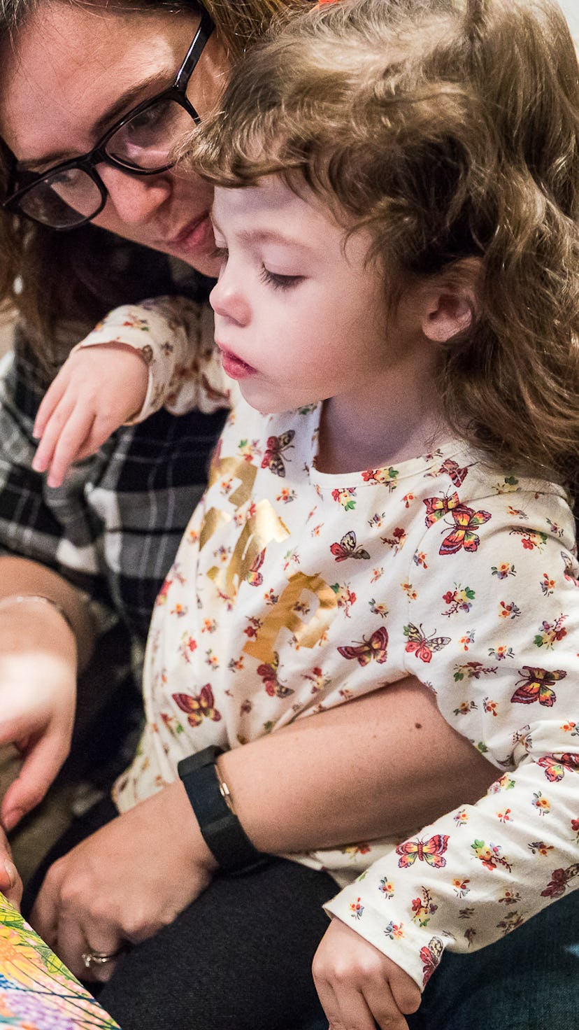 A mother holding her daughter who has Epilepsy as they read a book about flowers together