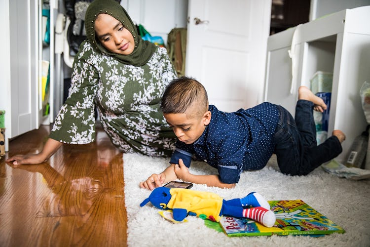 A mother sitting on the ground with her son diagnosed with Nicolaides-Baraitser syndrome is playing ...