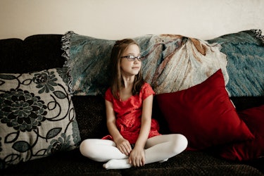 Fiona wearing a red dress and glasses sitting on the sofa 