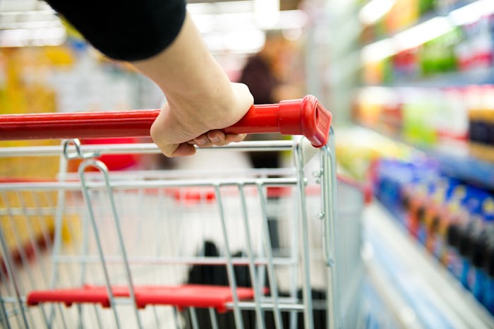 view of a shopping cart going down a grocery store aisle from behind