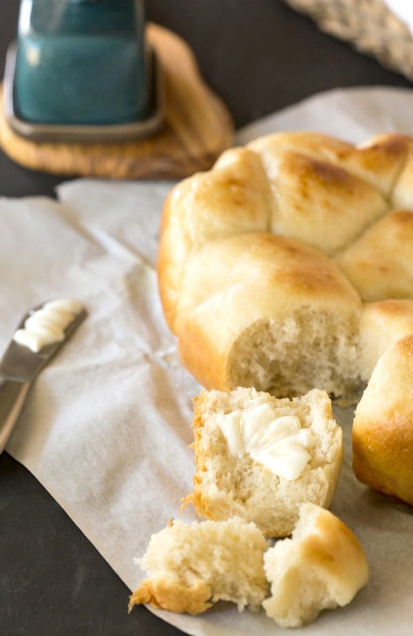 soft dinner rolls on a cloth next to a butter knife and butter dish