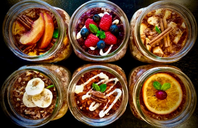 aerial view of an assortment of 6 jars with oatmeal garnished with different fruits or nuts