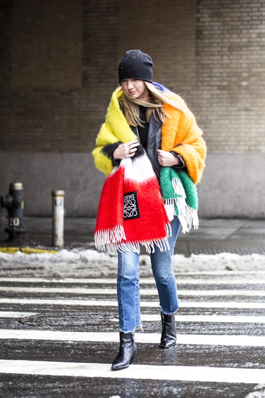 A blonde walking the street in jeans, leather jacket and a colorful oversized scarf