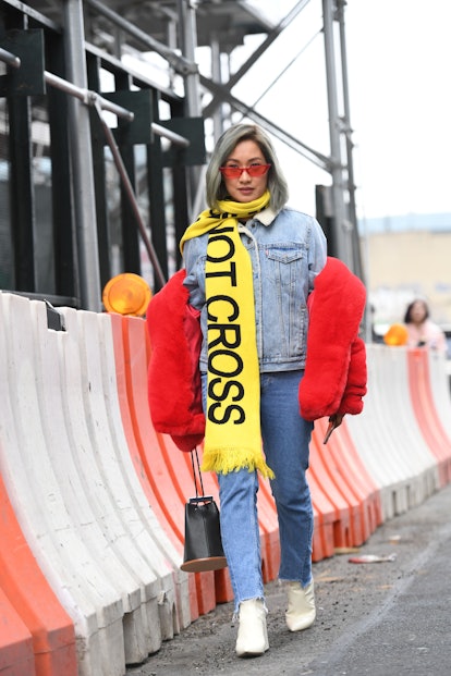 A blonde woman wearing all-denim look paired with a red faux fur coat and a yellow graphic scarf