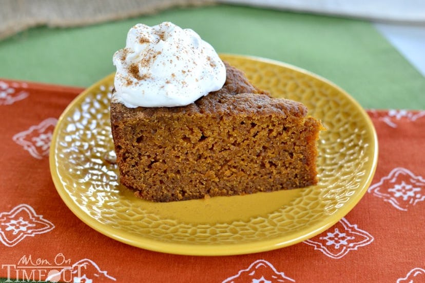 slice of pumpkin bread on a yellow plate topped with whipped cream and cinnamon powder
