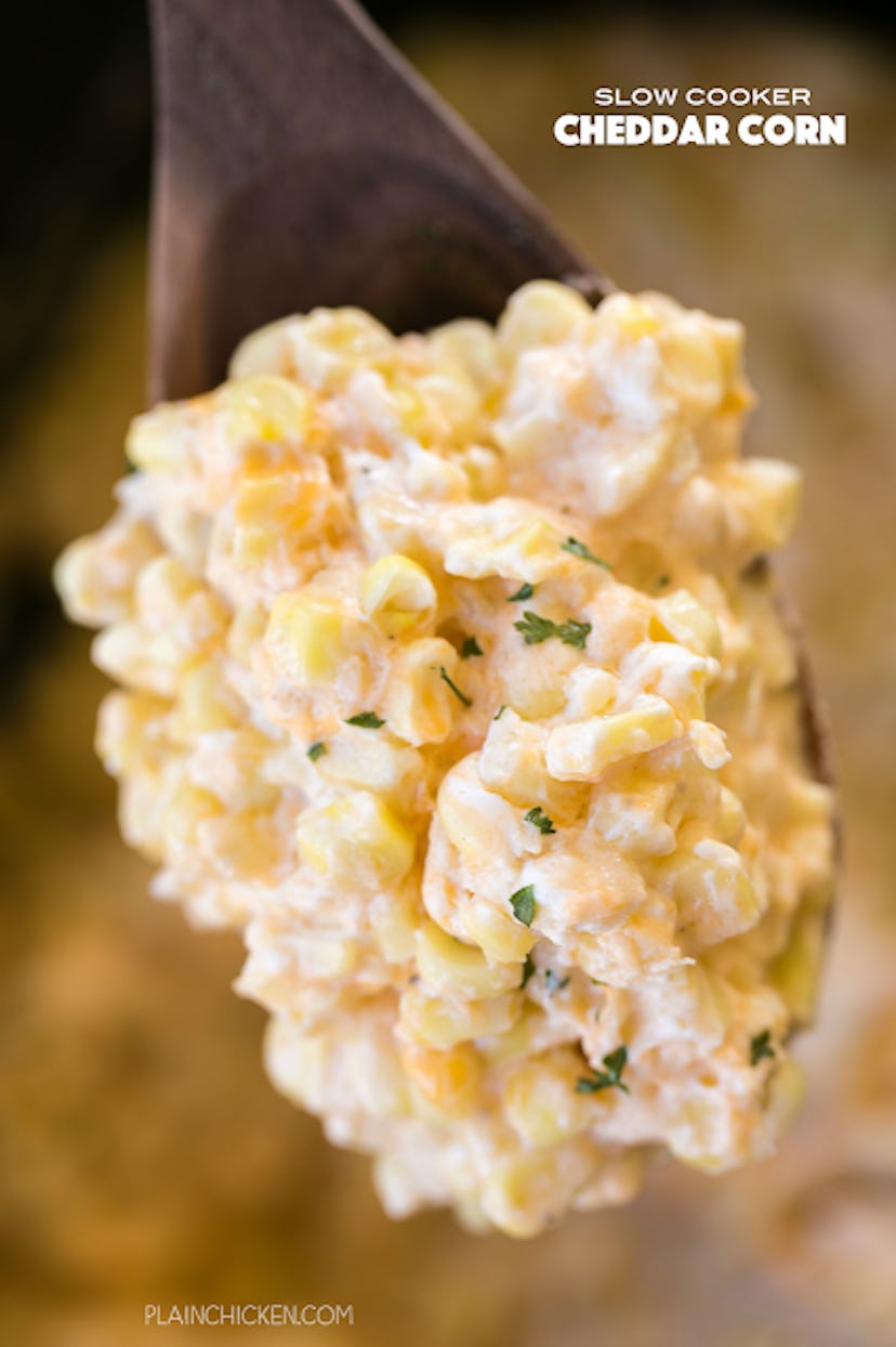 close up wooden spoon full of corn in a creamy cheese 