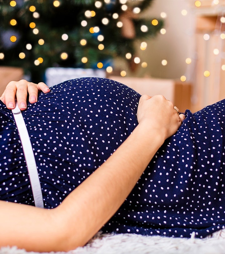 a pregnant woman lying in front of a Christmas tree