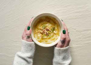 Female hands holding a bowl of cauliflower soup