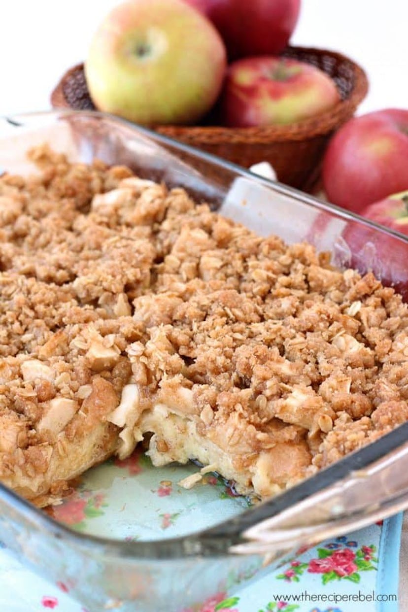 glass pan of apple crisp french toast with slice missing and apples in the background