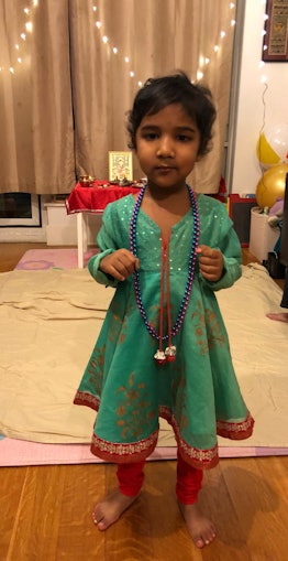 Shelly Agarwala‘s daughter dressed in traditional Indian clothing with purple and blue necklaces aro...