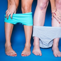 Two people pose knees-down with their underwear lowered in front of a blue background to get checked...