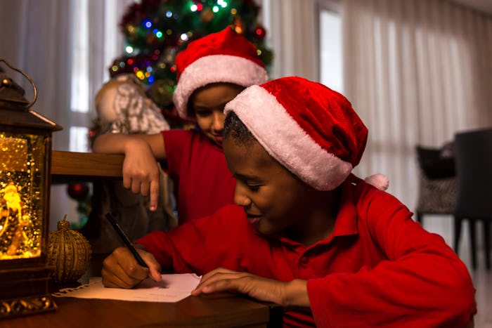 kid wearing santa hat, writing his wishlist to santa