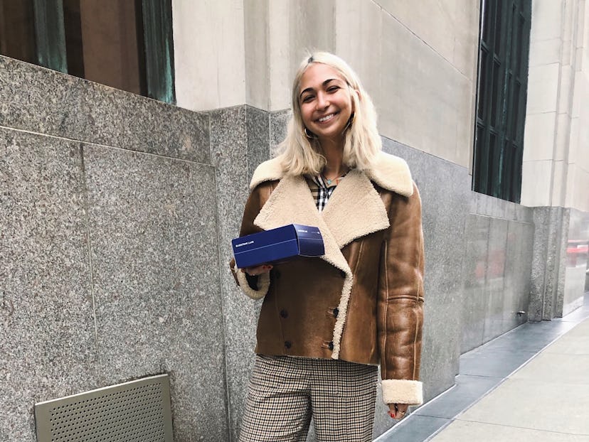 Iman Hariri-Kia standing in front of building with a blue box in hand 