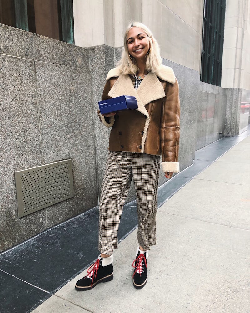 Iman Hariri-Kia standing in front of building with a blue box in hand 