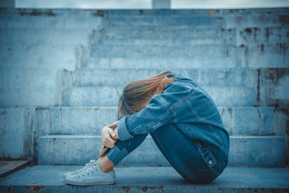 Girl sitting alone at outdoor stairs experiencing a rage attack