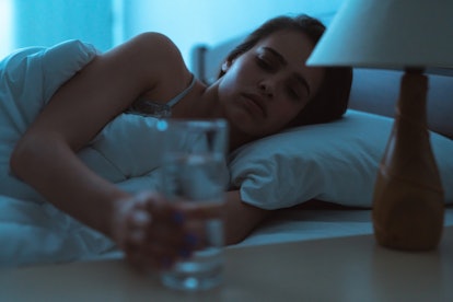 Depressed lady drinking water while in bed 