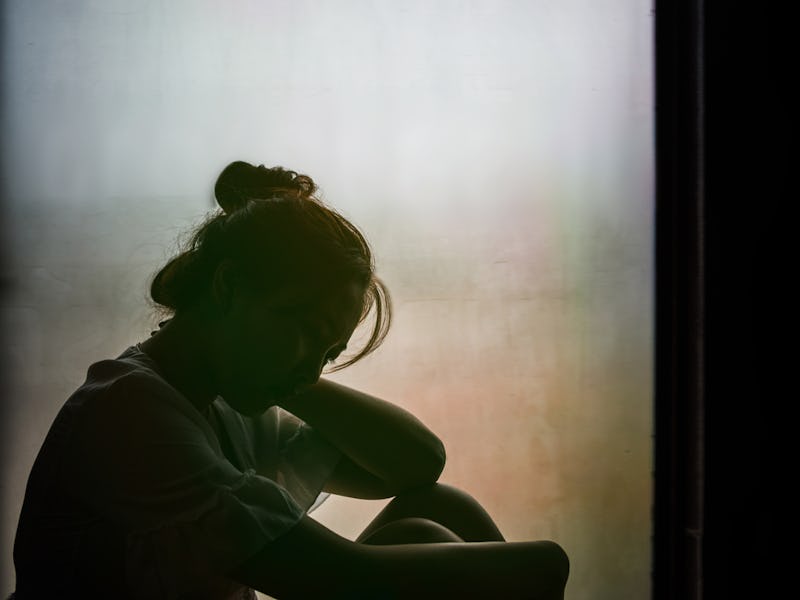 A girl sitting on the floor alone in the dark