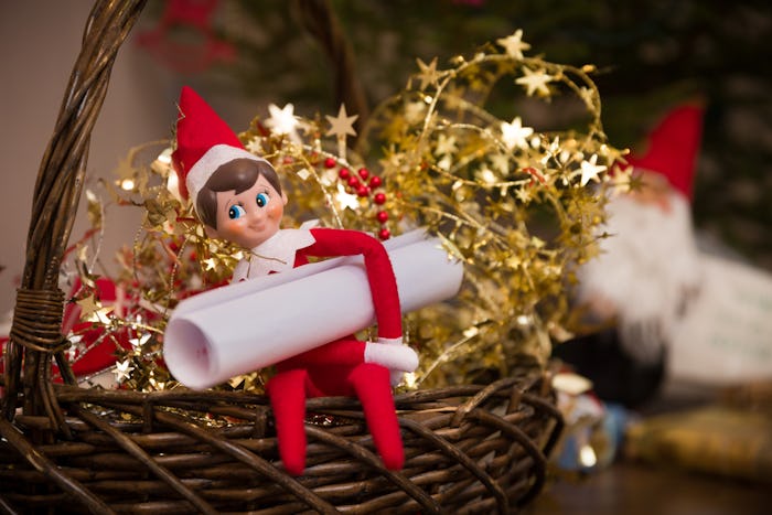 elf on the shelf doll in a basket with gold star garland and a letter