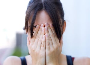 A woman covering her face due to her alcohol-triggered migraine 