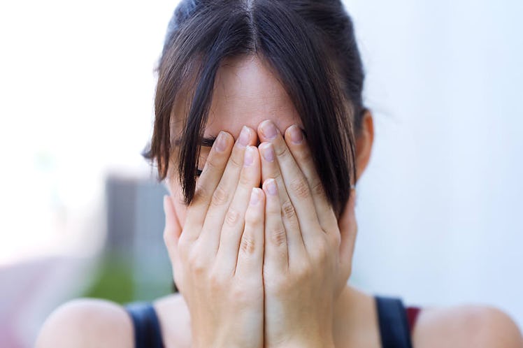 A woman covering her face due to her alcohol-triggered migraine 