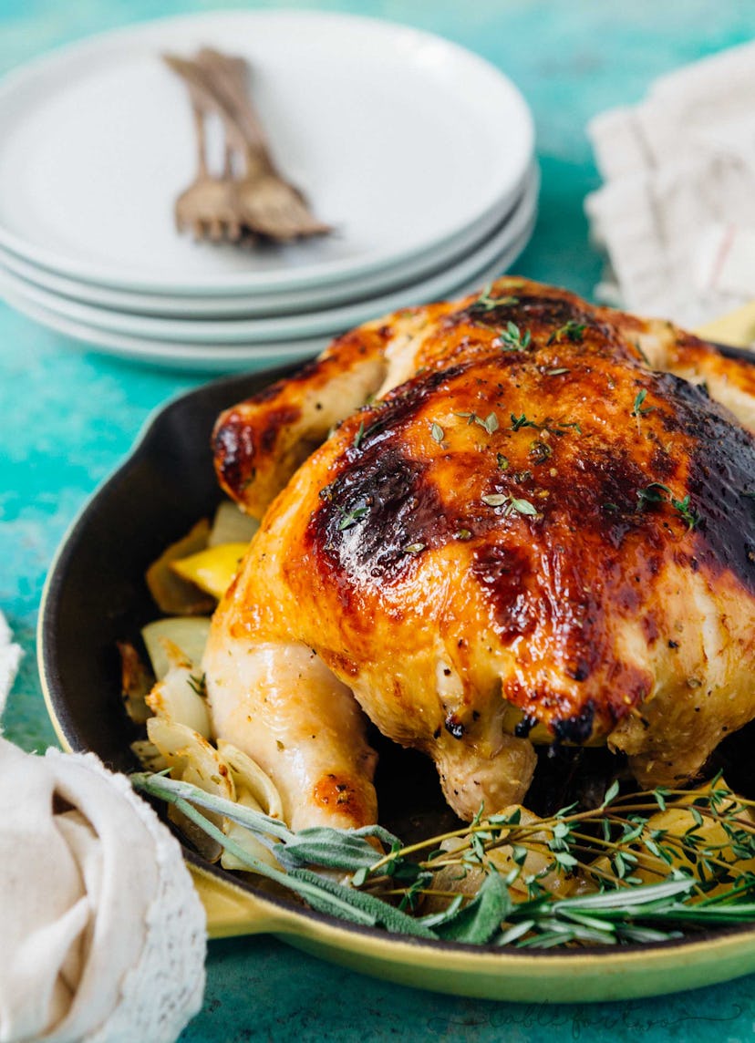 whole roasted chicken with rosemary in a pan being served on a table