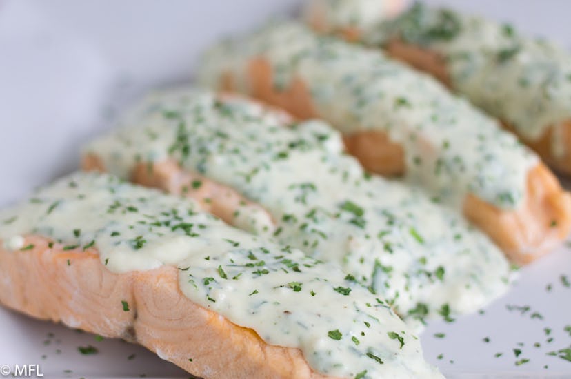 cooked salmon with a creamy cheese sauce on top