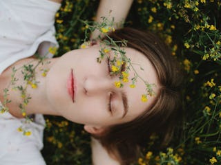 A woman lying on the grass covered in yellow flowers.