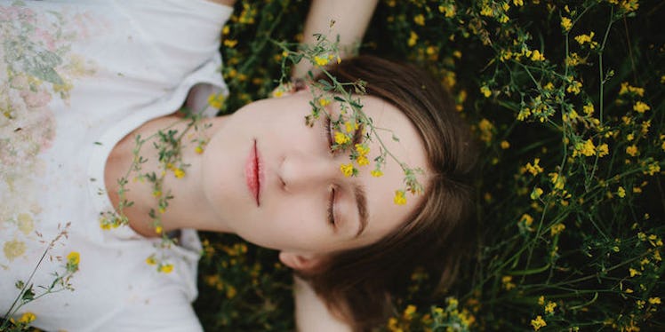 A woman lying on the grass covered in yellow flowers.