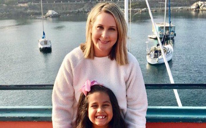 A woman with her six-year-old daughter in a marina with boats behind them